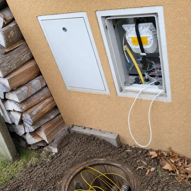 Raccordement fibre optique en façade : niche technique ouverte et chambre extérieure avec câbles fibre